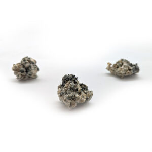 Three small clumps of dried, enigmatic material, resembling the potent Enigma (Copy) strain, are scattered against a white background.